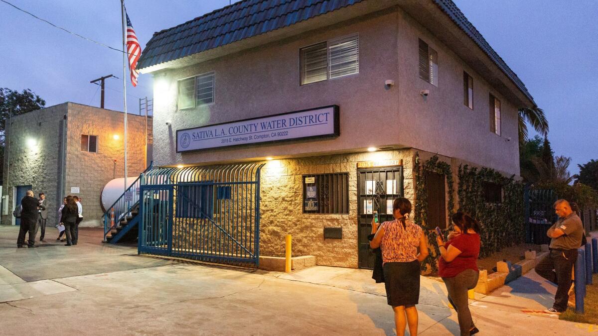 Residents watch the board of the Sativa Los Angeles County Water District leave the district's headquarters after a special closed-door meeting in June.