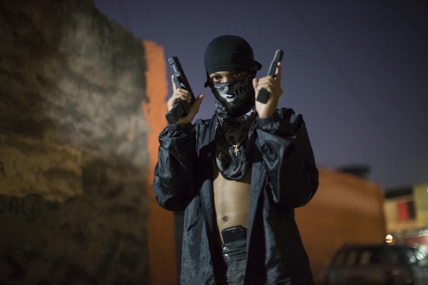 11/julio/2016: Un joven traficante de drogas enmascarado posan para fotos con sus armas en una favela de Río de Janeiro, en Brasil. Los jóvenes trabajan como guardias de seguridad, vigías y distribuidores para los capos de la droga en las favelas.