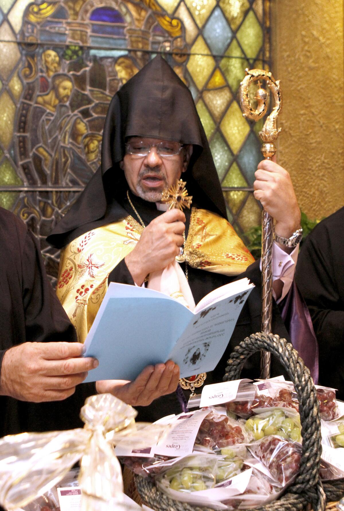 Archbishop Moushegh Mardirossian, Prelate of the Armenian Apostolic Church of the Western United States, center, performs the annual Armenian harvest-time celebration blessing of the grapes at Glendale Adventist Medical Center in Glendale on Wednesday, Aug. 13, 2014. Baskets with about 300 bags of grapes were blessed.