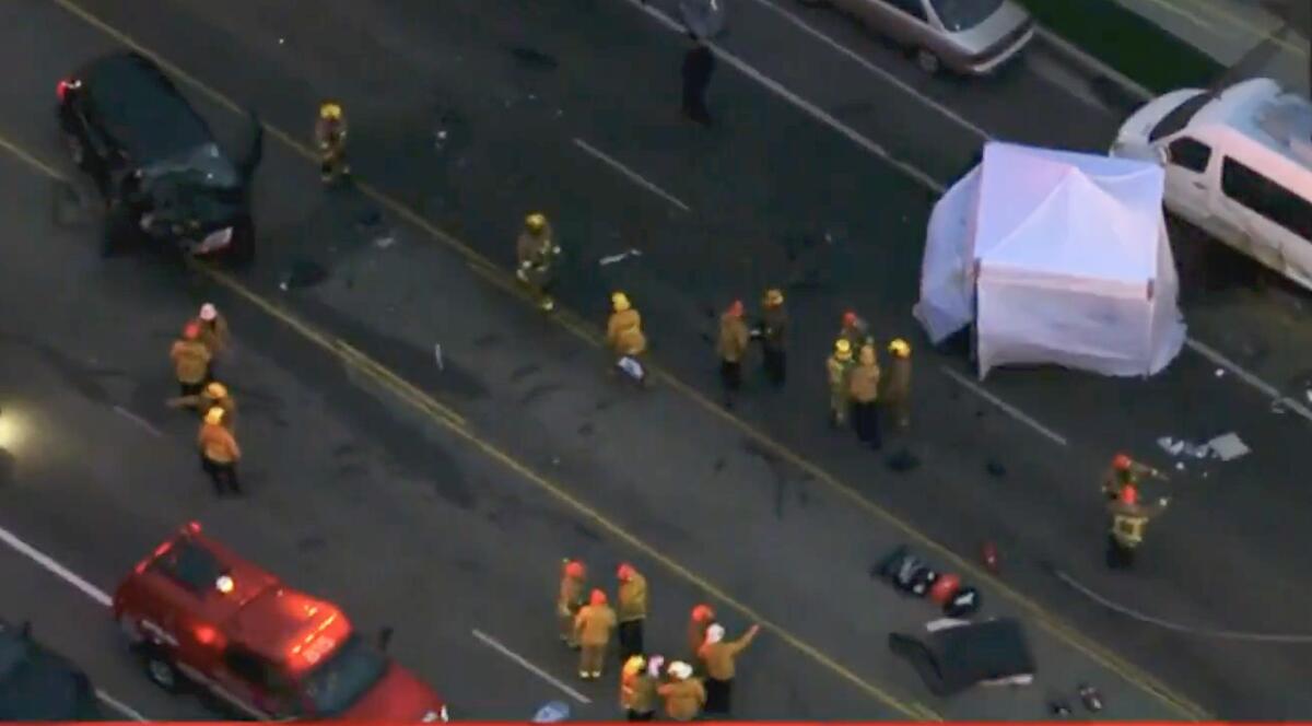 An aerial view of firefighters at a debris-strewn crash scene with a white tent 