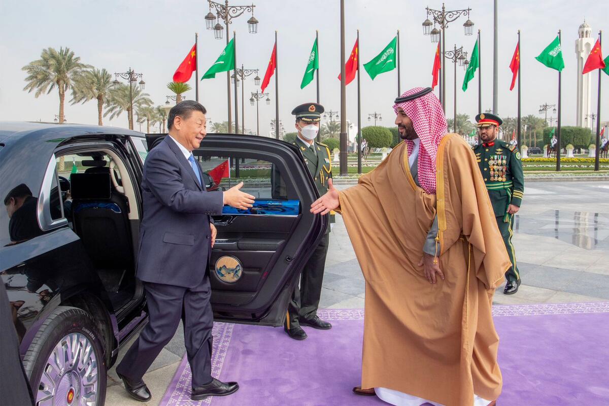 A man in business suit about to shake hands with a man in Middle Eastern robes after stepping from a limousine