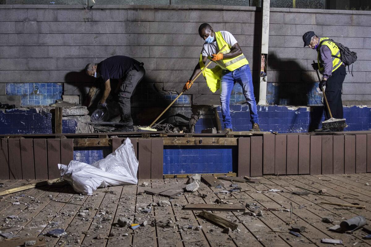 A police officer, left, inspects the damage at a site in Ashdod, Israel, that was hit by rocket fire on Tuesday.