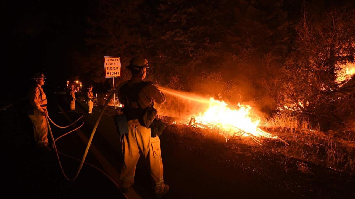 Firefighter Shawn Lee, right, and his colleagues try to contain flames from the Carr fire as it spreads toward the town of Douglas City near Redding on July 30.
