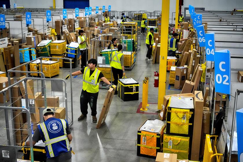 ARCHIVO - Empleados de Amazon cargan paquetes en carritos antes de ponerlos en camiones para su distribución durante el Prime Day de Amazon, en la estación de entrega DAX7 de la compa?ía, el martes 16 de julio de 2024, en South Gate, California. (AP Foto/Richard Vogel, Archivo)