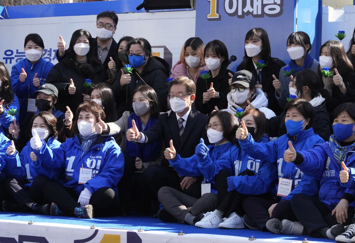 Lee Jae-myung, center, the presidential candidate of the ruling Democratic Party, poses with his supporters during a presidential election campaign in Seoul, South Korea on March 3, 2022. Just days before March 9 election, Lee and Yoon Suk Yeol from the main conservative opposition People Power Party are locked in an extremely tight race. (AP Photo/Ahn Young-joon).
