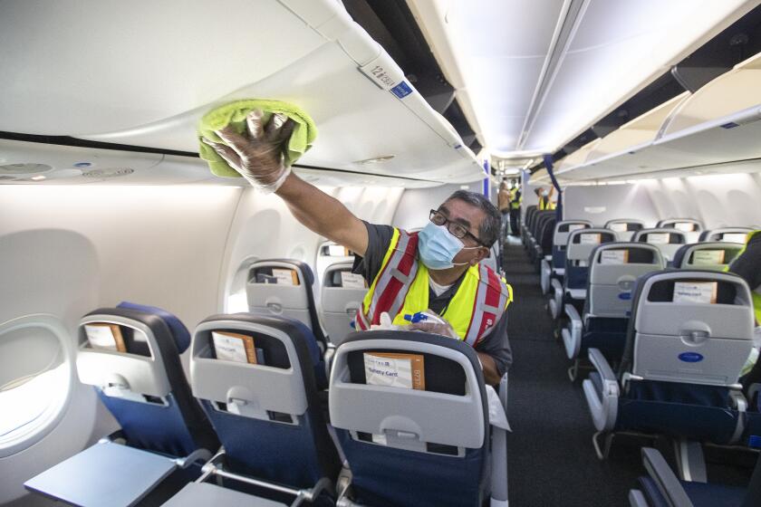 LOS ANGELES, CA -JULY 09, 2020: Cleaning supervisor Jose Mendoza disinfects the cabin area of a United Airlines 737 jet before passengers are allowed to board at LAX on Thursday, July 9, 2020 in Los Angeles, CA. (Mel Melcon / Los Angeles Times)