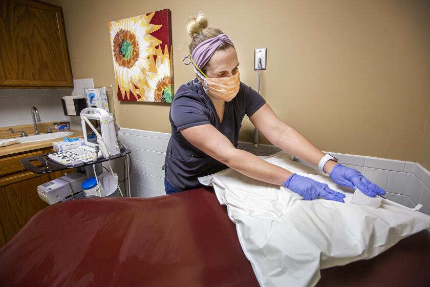 Trust Women Wichita Clinic staff member Lindsay Mills disinfects an examining room Tuesday. The abortion clinic is seeing more patients from out-of state due to anti-choice measures in those states.