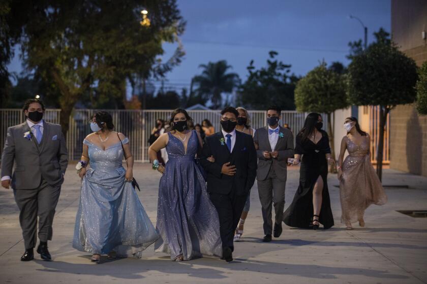 LYNWOOD, CA - MAY 21: Students walk onto campus wearing masks and formalware on Friday night, May 21, 2021 in Lynwood, CA. Lynwood High School is having a prom at the campus. Students are gathering together for the first time in a year to celebrate their prom during the ongoing pandemic. (Francine Orr / Los Angeles Times)