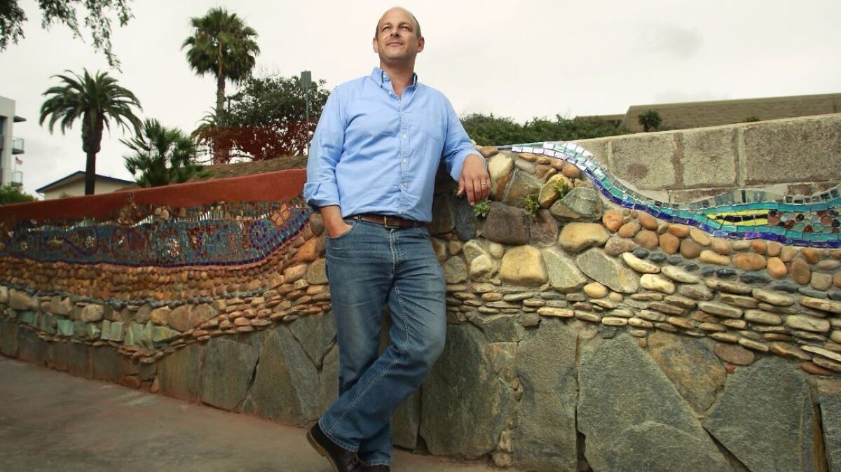 Matt D'Arrigo, founder and CEO of A Reason To Survive art center now located in National City, stands next to a rock and tile mural created by artists in the nonprofit program. He announced he is stepping down in July.