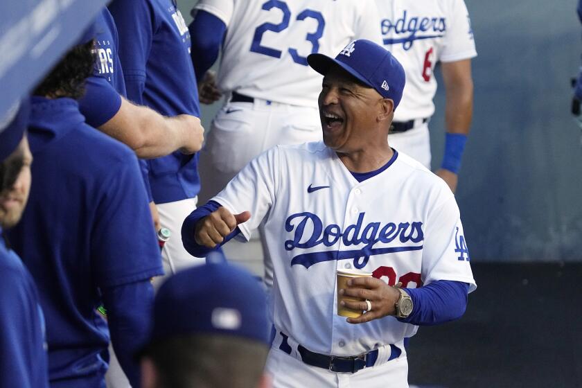 Dodgers manager Dave Roberts laughs as he walks through the dugout prior to a game 