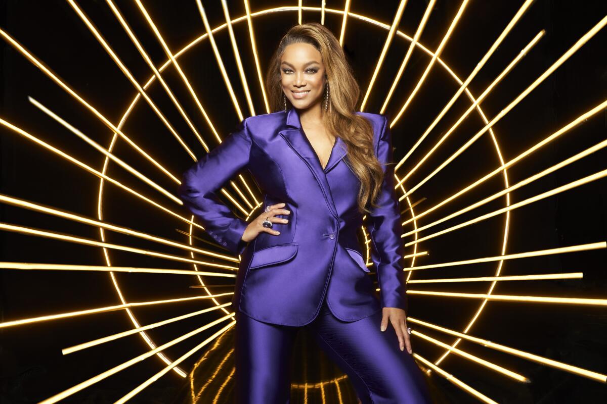 A woman wearing a sleek purple suit against a bright background