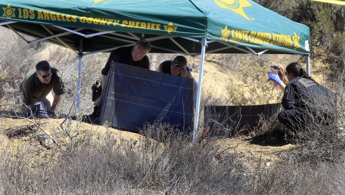 Investigators from the Los Angeles County Sheriff's Department study the scene off Lake Hughes Road in Castaic where a burned body was discovered.