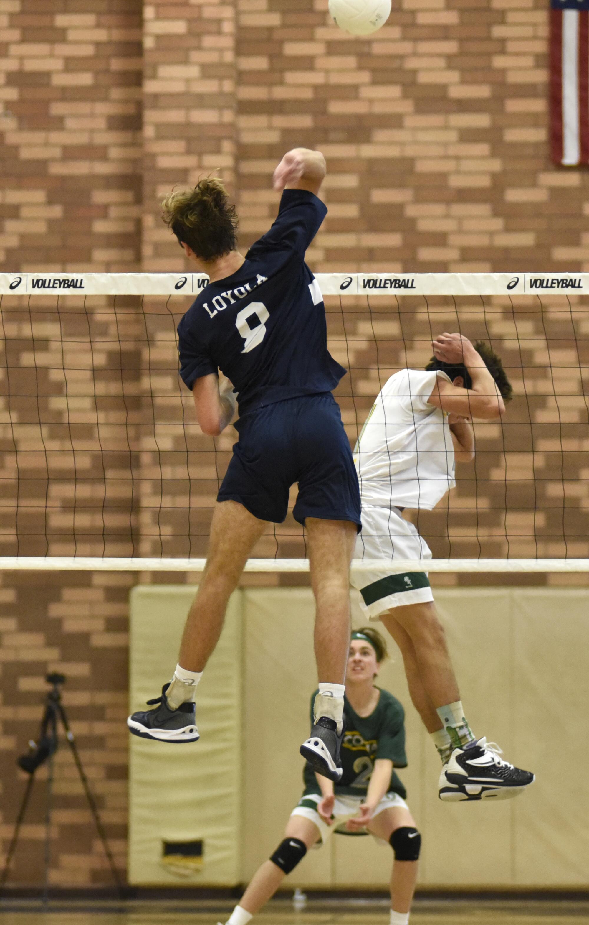 A Mira Costa blocker shields his head as he turns away from a spike attempt by Loyola's Dillon Klein on March 18, 2022.