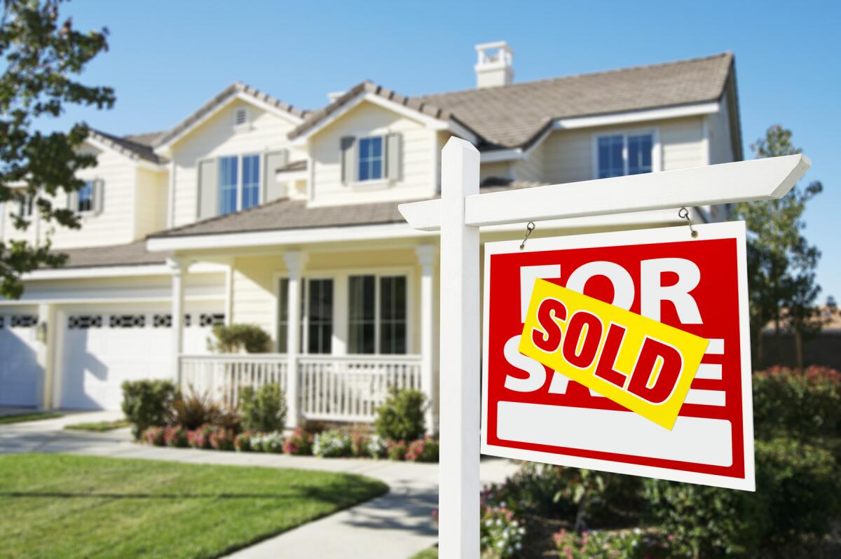 A "Sold" sign is hanging outside a home.