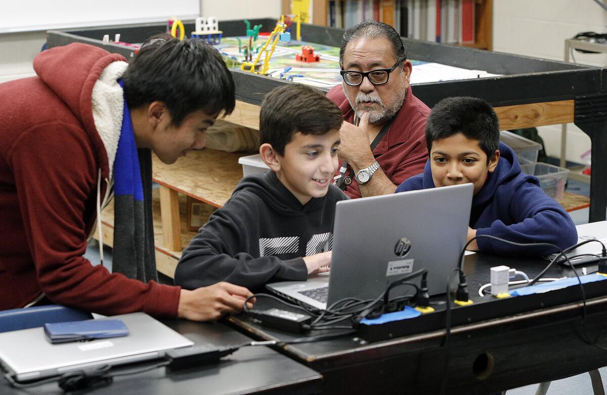 Robotics instructor Randy Kamiya watches students John Nguyen, 13, Avakeem Avakian, 11, and Ibrahim Ahmad, 13, work with a Lego robotics program during a class at Roosevelt Middle School on Monday.