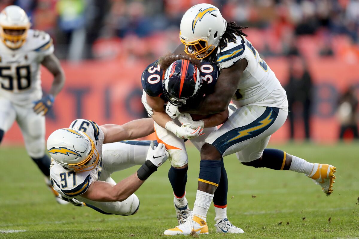 Denver Broncos' Phillip Lindsay (30) is tackled by Chargers' Joey Bosa (97) and Melvin Ingram III (54) in the third quarter on Sunday in Denver.
