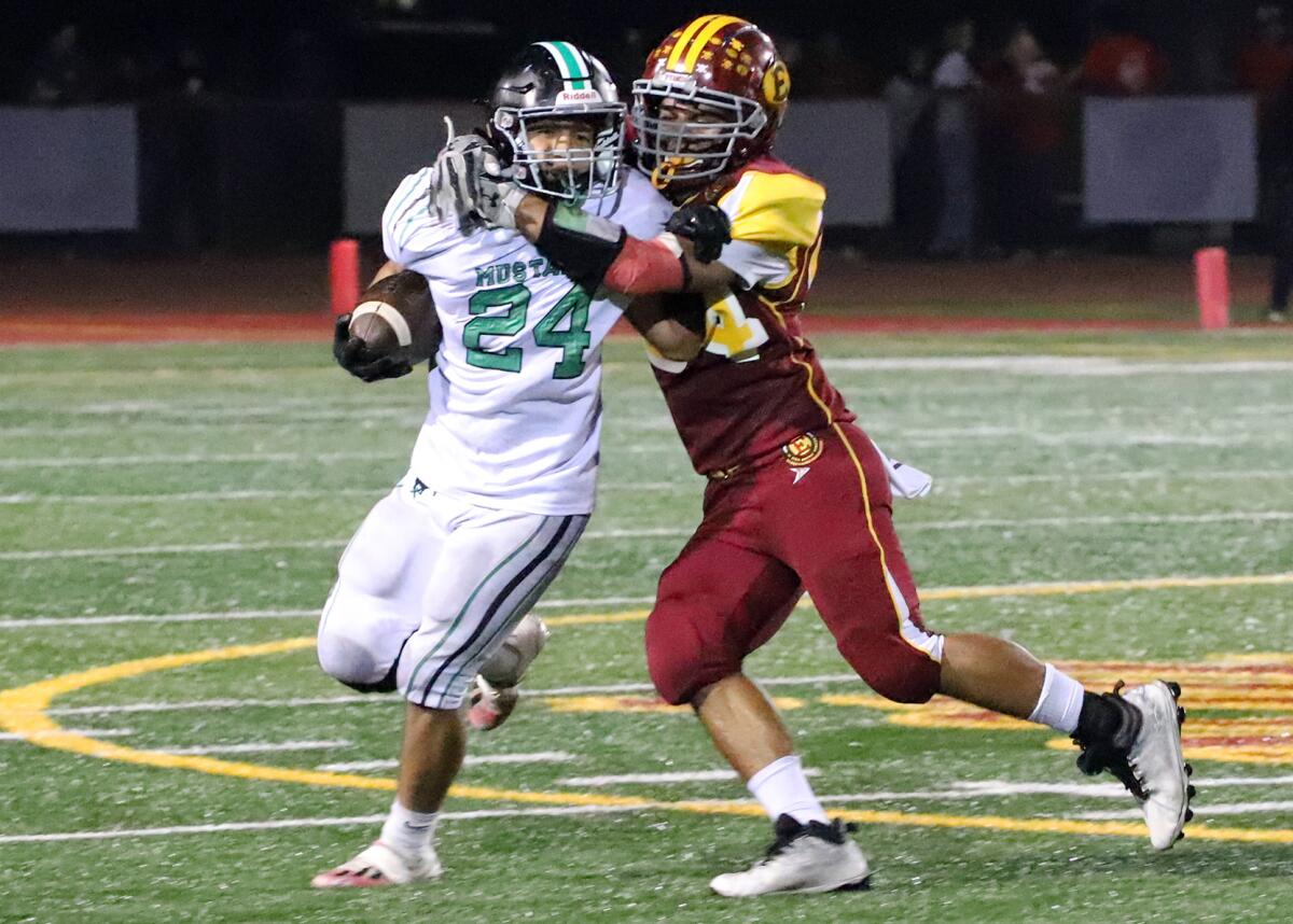 Costa Mesa's Diego Ramirez (24) tries to run past Estancia's Alexis Galindo (24) in the Battle for the Bell football game.