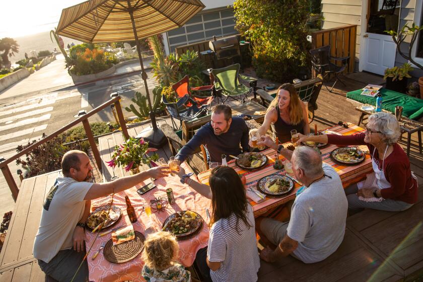 MANHATTAN BEACH, CA - NOVEMBER 26: Aaron Liggett, left, makes a toast as Thanksgiving dinner is served, spending it with, clockwise from Aaron, brother Austin and his wife Nina, parents David and Robin Liggett and his wife Michelle and son Waylon, outside his parent's home on 9th Street in Manhattan Beach, Thursday, Nov. 26, 2020. David and Robin had to cancel their 50th wedding anniversary this year due to COVID-19 and would usually have 25-30 people over for Thanksgiving, where she annually makes the family receive for Swedish meatballs, which they were enjoying tonight. (Jay L. Clendenin / Los Angeles Times)