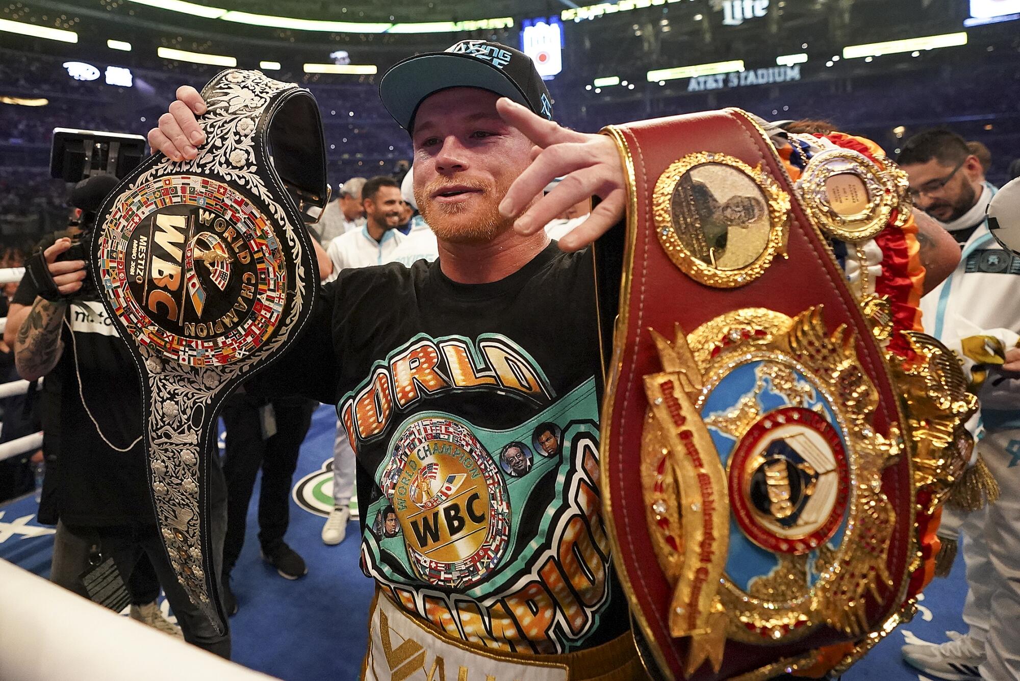 Canelo Álvarez holds up his belts