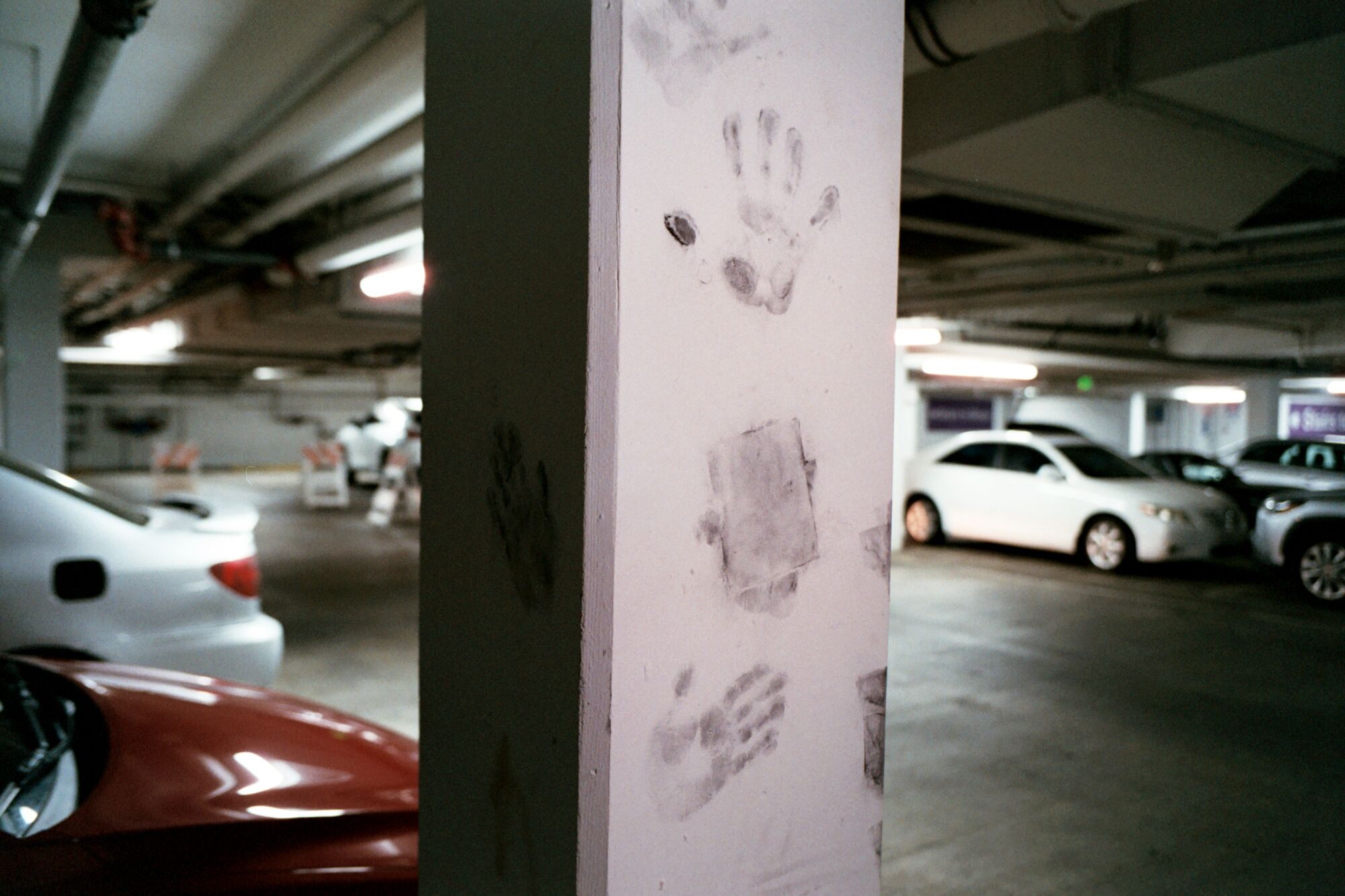 Empreintes de mains grises sur une colonne en béton dans un garage de stationnement