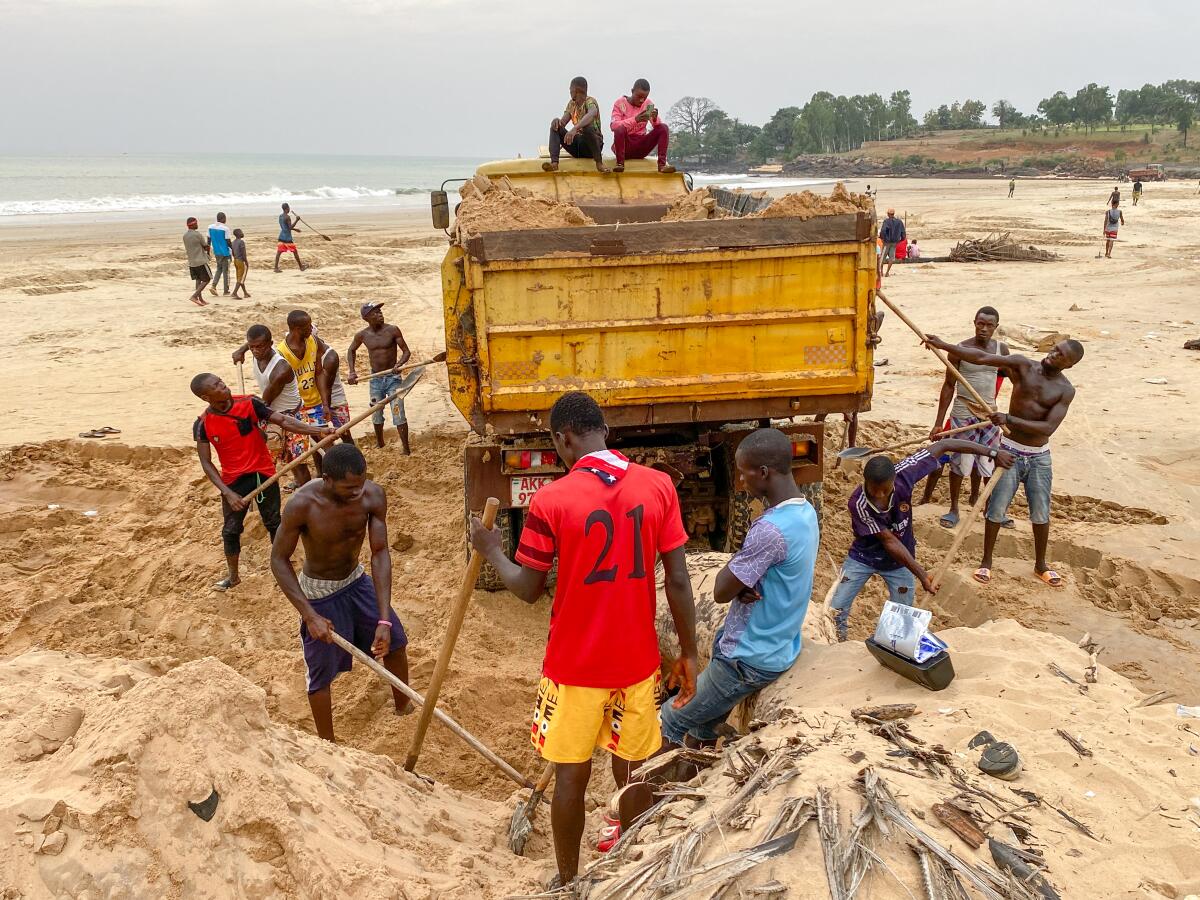 Sand miners shovel sand into a truck on John Obey beach in Sierra Leone in December.