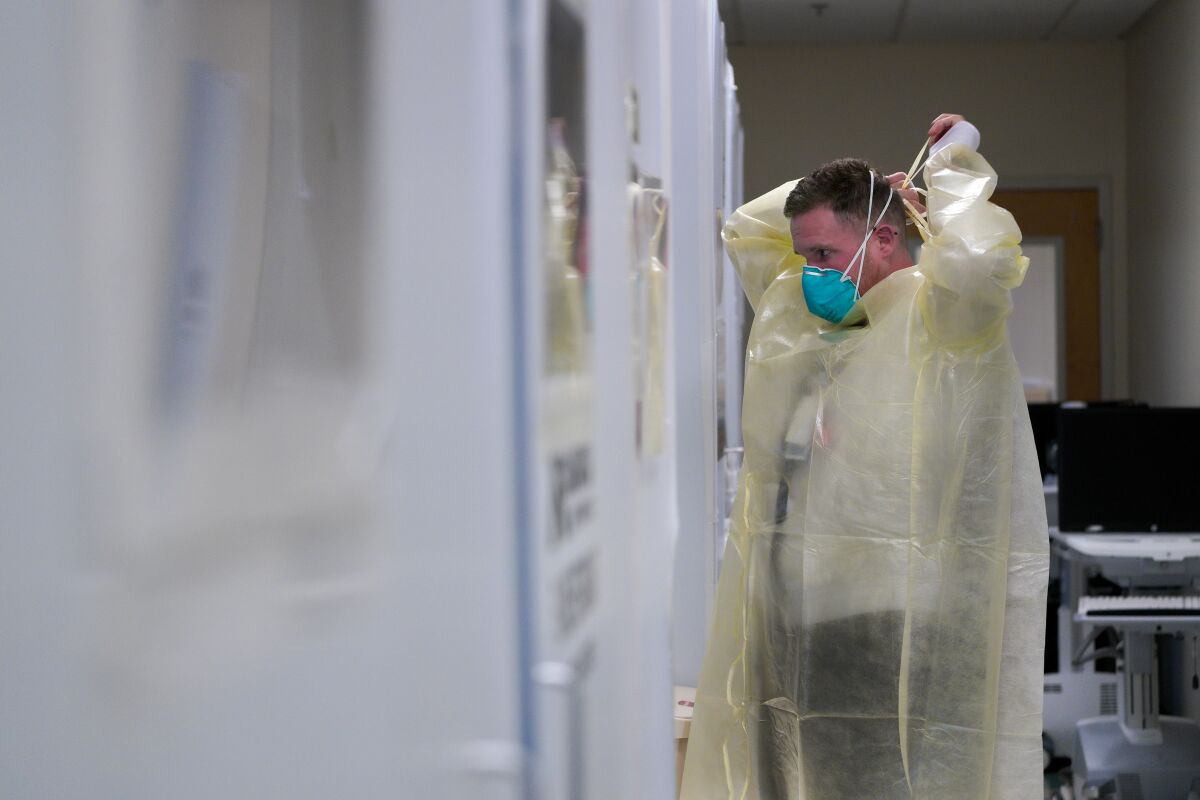 Registered nurse Kevin Sabllith puts on his PPE before entering his patient's room.