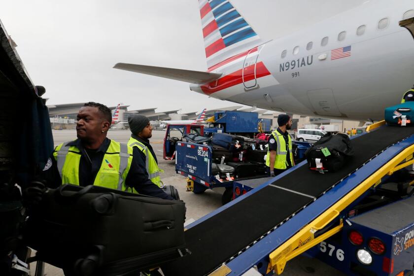 Workers unload baggage from American Airlines Flight 998 from Orlando, Fla., to Los Angeles International Airport. The crew of four has about 35 minutes to unload up to 5,000 pounds of luggage, cargo and mail.
