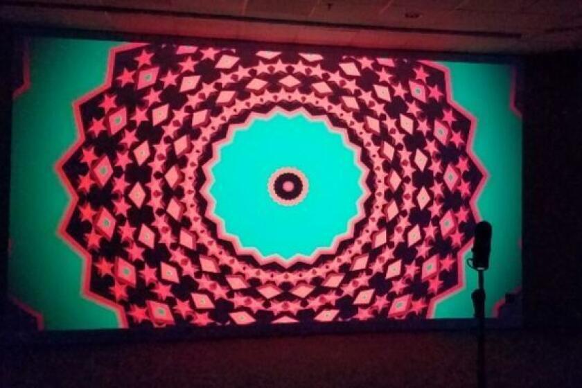 A microphone stand in front of Hank Willis Thomas' psychedelic video projection invites visitor participation.