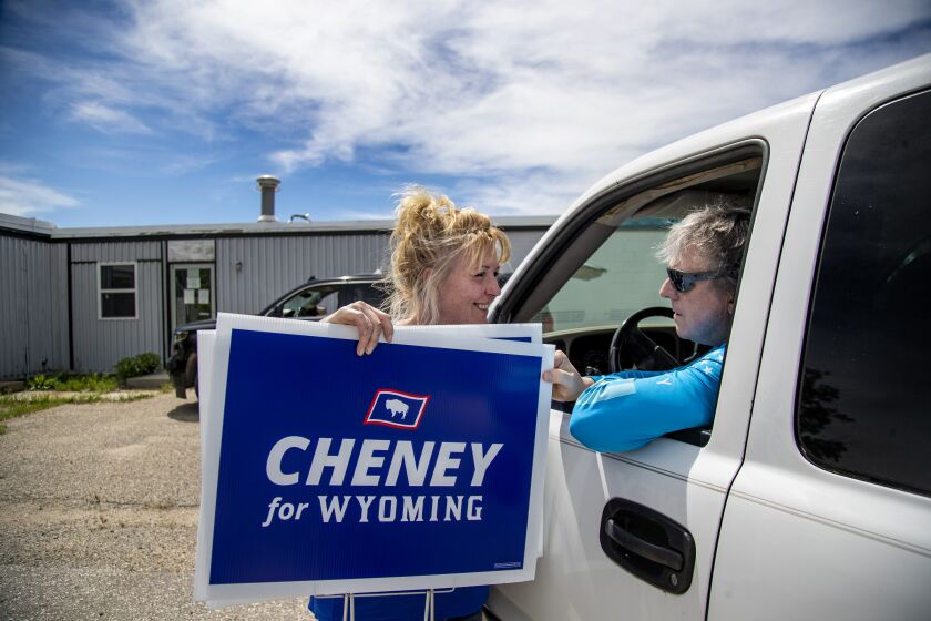 CASPER, WY - JUNE 10, 2022: Liz Cheney political director Amy Womack gives resident Neal Hibschweiler a "Cheney For Wyoming" sign for his front lawn on June 10, 2022 in Casper, Wyoming. Hibschweiler, a registered Democrat, just happened to be driving by campaign workers when he stopped to ask for the signs. After watching Cheney on TV during the Jan. 6 Hearings, he decided to send her campaign $25.(Gina Ferazzi / Los Angeles Times)