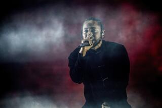 Kendrick Lamar rapping into a microphone on a dark smoky stage with a dark red backdrop