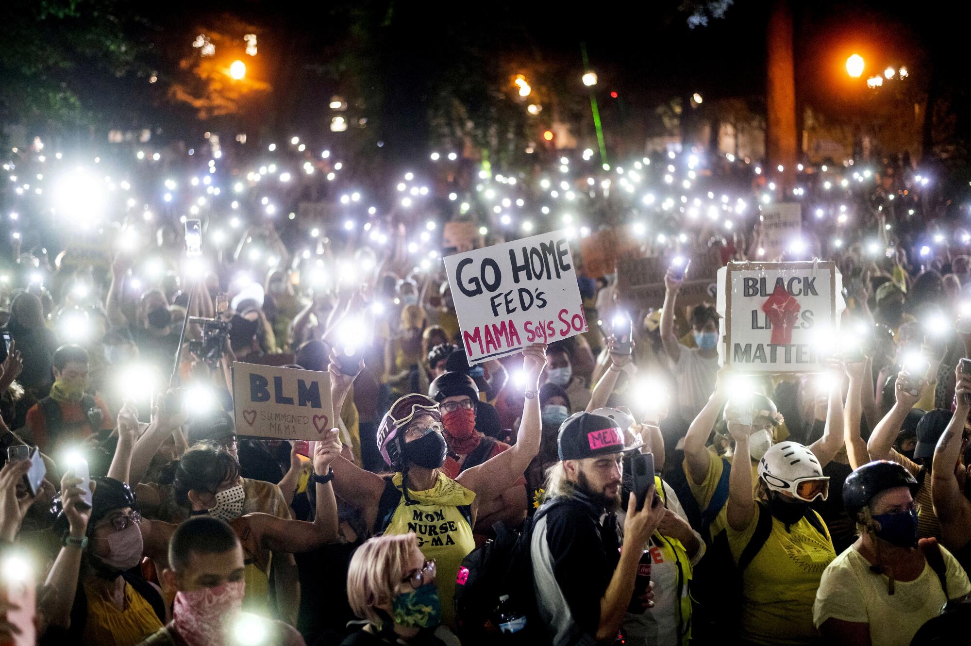 Hundreds of protesters hold their phones aloft on Monday in Portland, Ore.