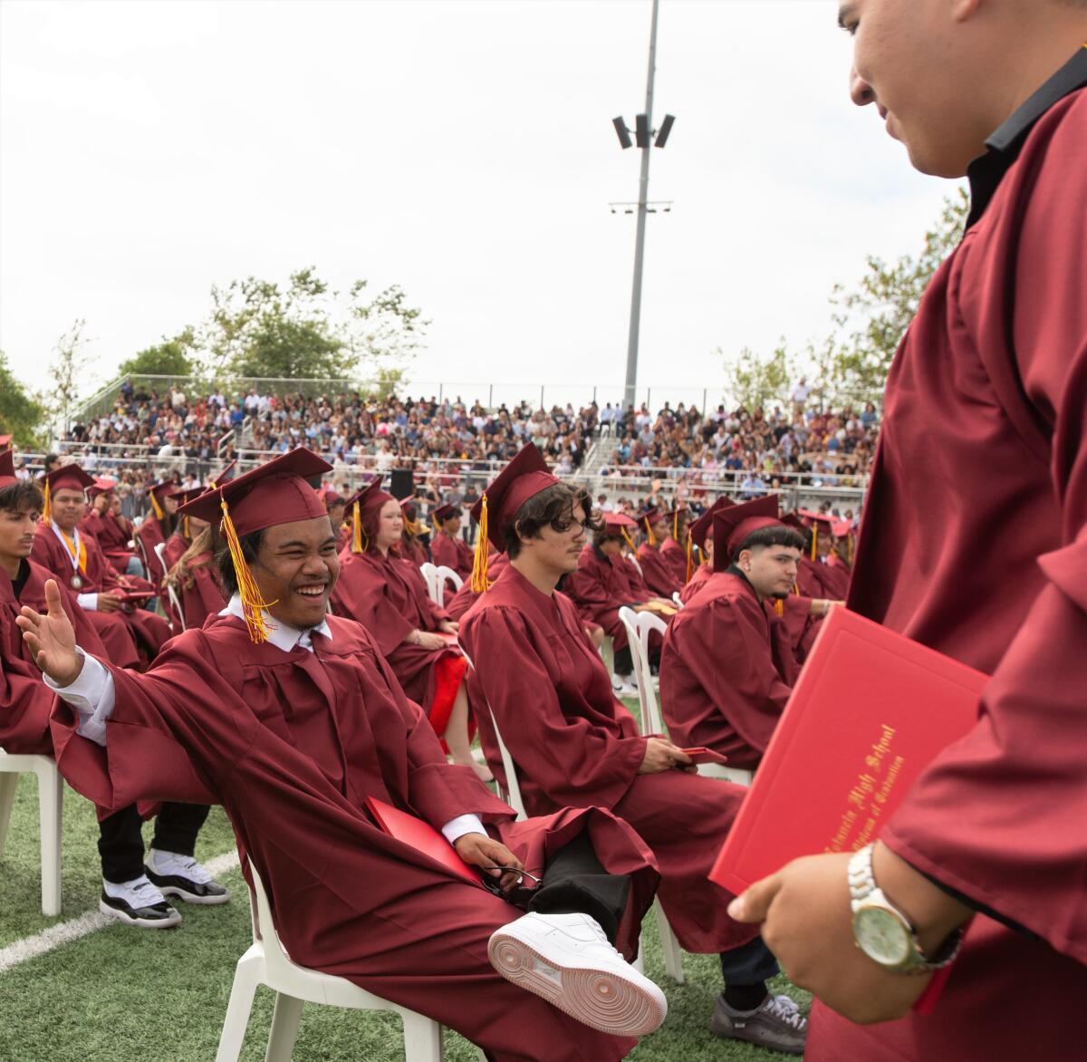Randy Harry offers a high five to Angel Torres during the Estancia High School graduation.