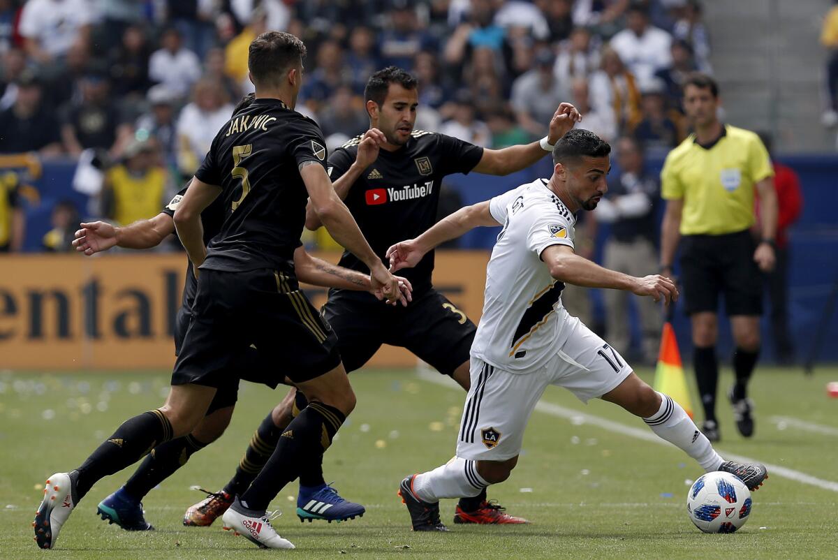 Galaxy midfielder Sebastian Lletget, right, attracts three LAFC defenders in the first half on Mar. 31 at StubHub Center in Carson. The Galaxy came from behind to win, 4-3.
