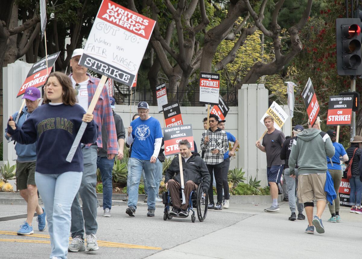 Striking workers walk and roll at a picket line.