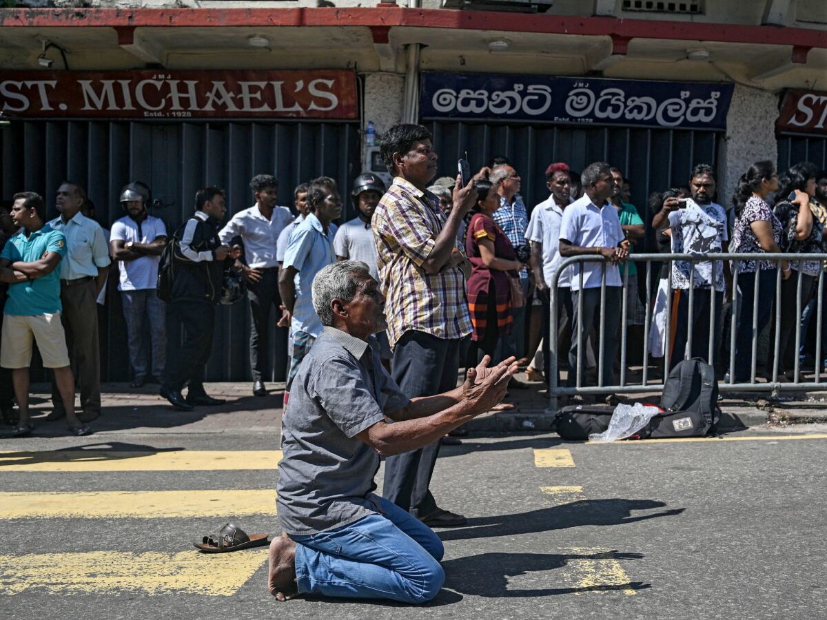 People pray outside St. Anthony's Shrine in Colombo a day after the building was hit by a bomb blast.