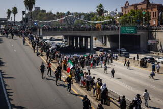 People walk on a roadway and a freeway.
