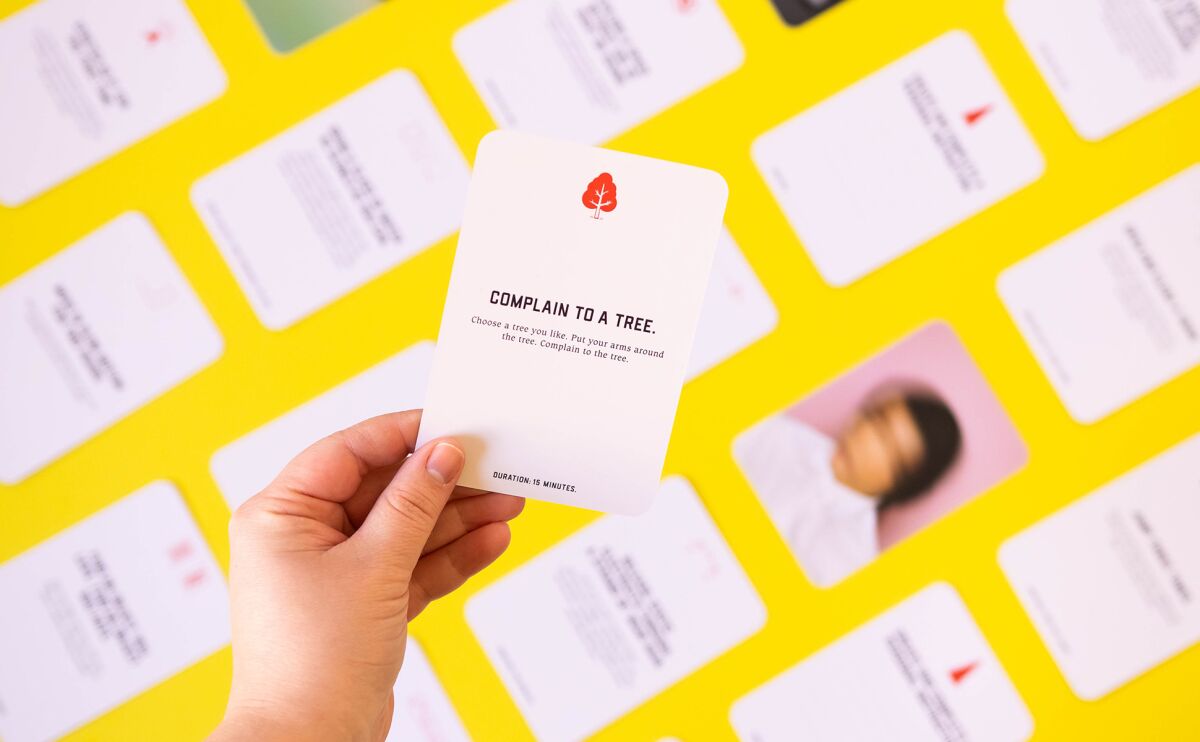 Close-up of a hand holding a card with the words "complain to a tree."