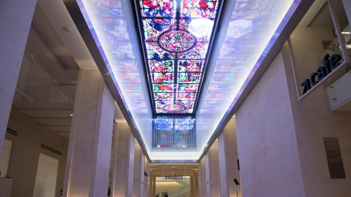 A digital screen runs the length of the museum lobby's ceiling.
