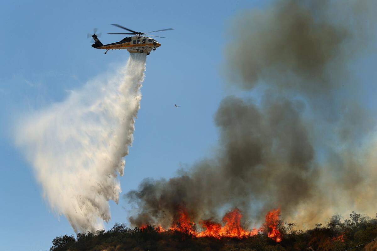 Firefighters in the air and on the ground work to control a fire that broke out near Duarte.