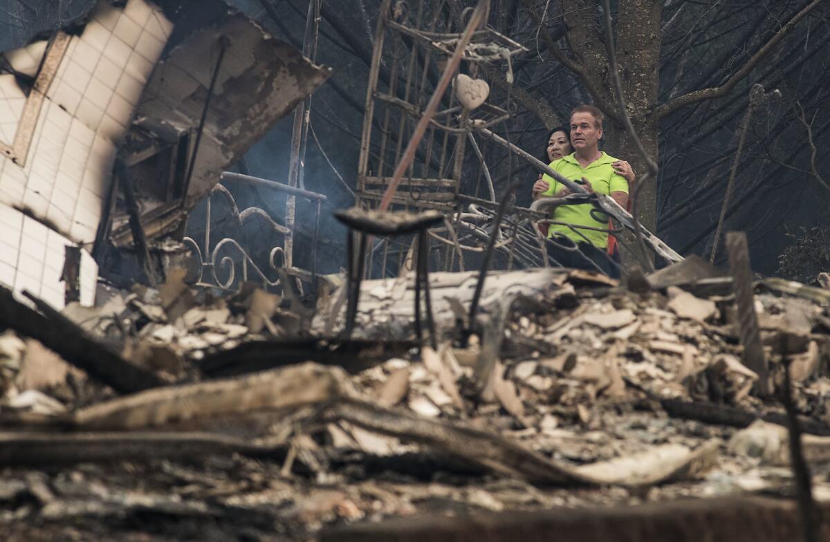 Mark Williams and his friend Norina Wong look over the destruction in a friends' neighborhood off Fountaingrove Parkway in Santa Rosa, Calif.