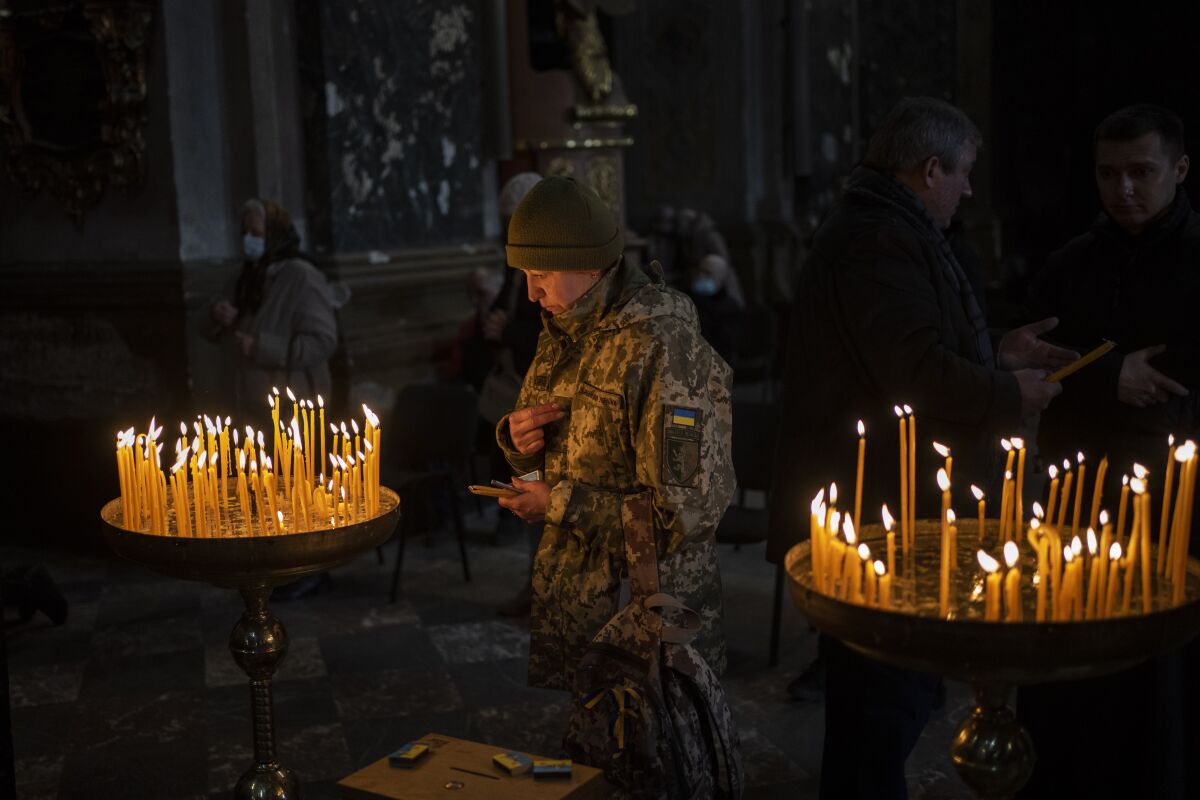 A Ukrainian woman dressed in military attire prays inside the Saints Peter and Paul Garrison Church in Lviv, western Ukraine, Sunday, March 6, 2022. (AP Photo/Bernat Armangue)