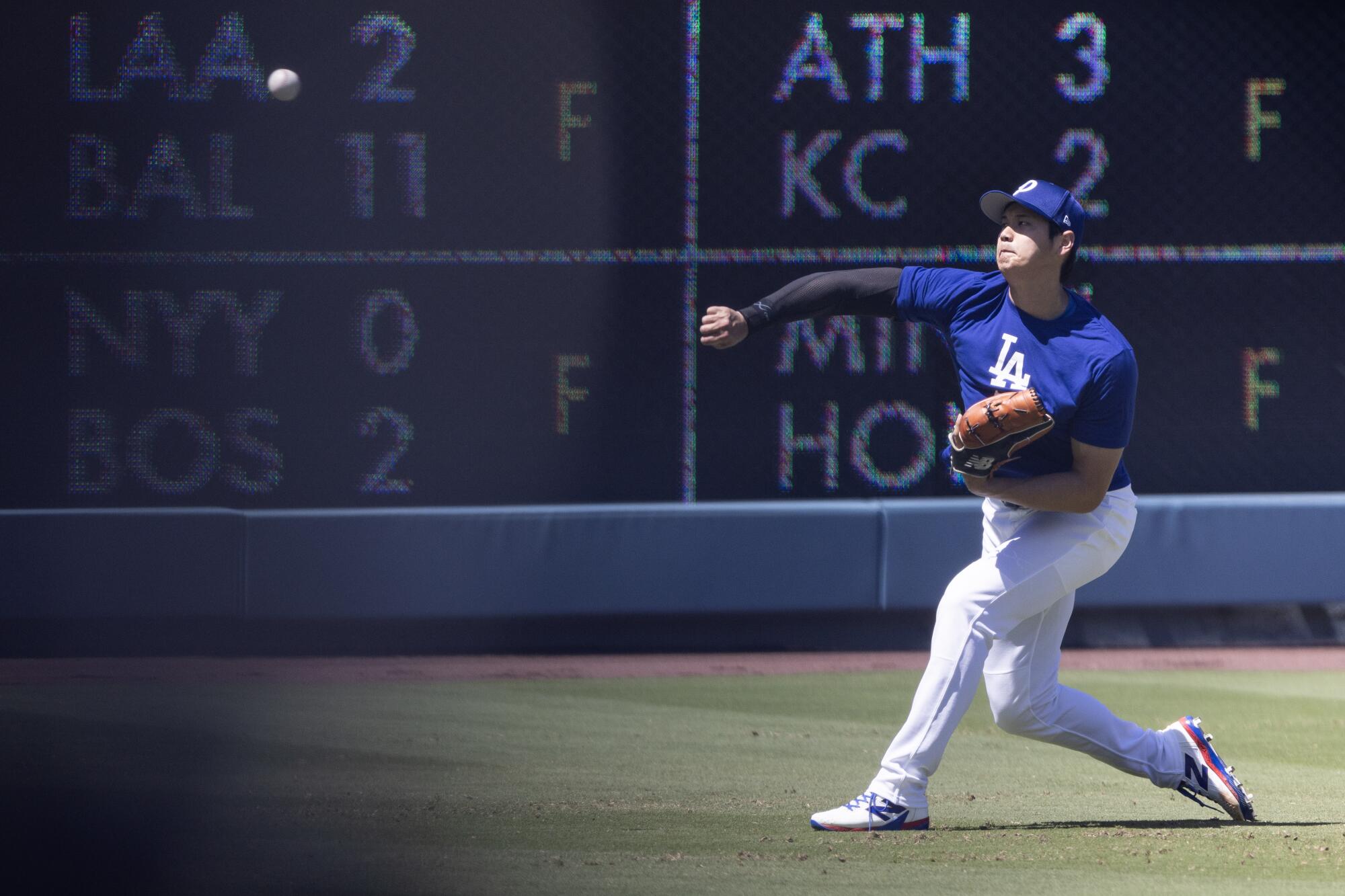 Dodgers star Shohei Ohtani throws in the outfield before Sunday's game against the San Francisco Giants at Dodger Stadium.