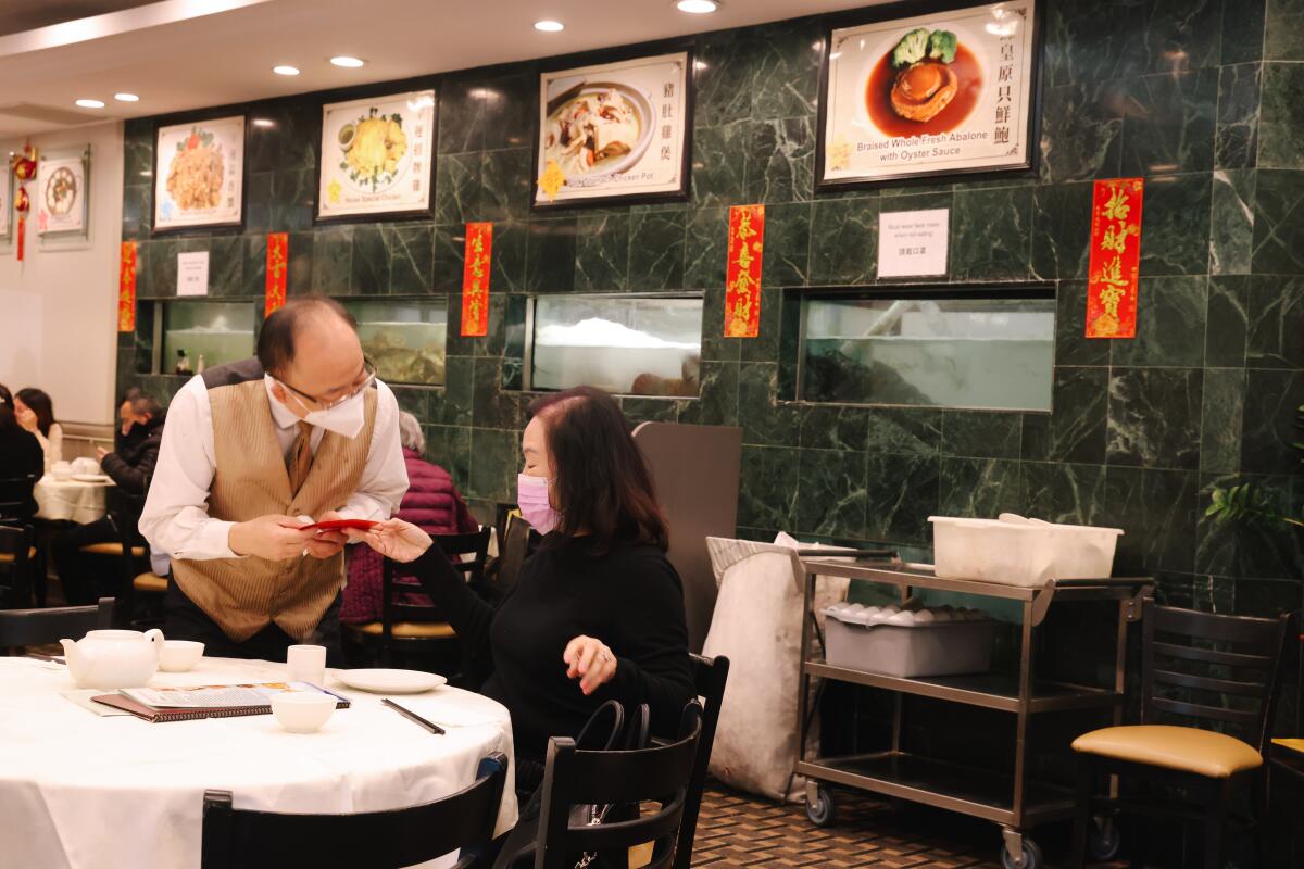 Tony Huang, left, receives a red envelope from customer Olivia Chang, right, at Taste of MP restaurant.