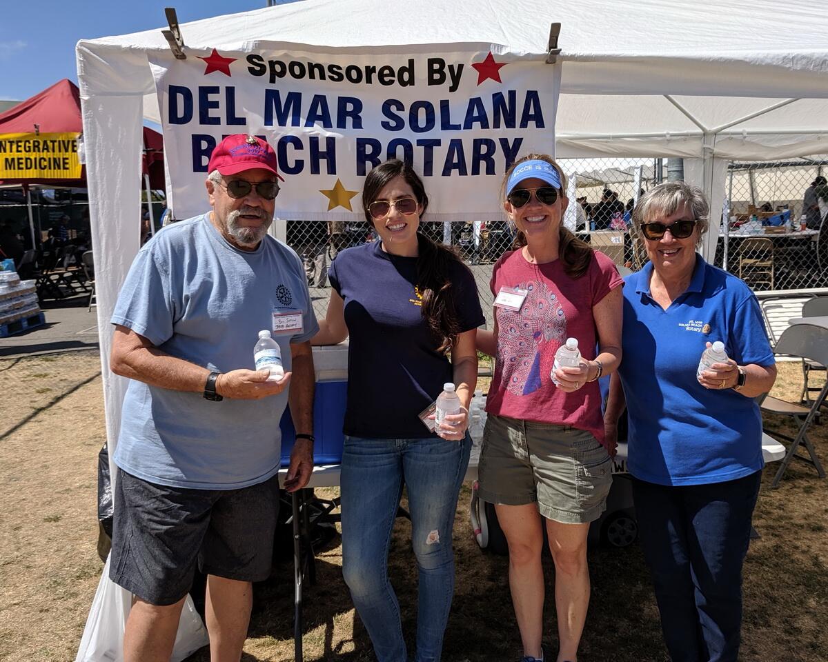 Del Mar-Solana Beach Past President and Marine Bill Sutton (left), organized and led 25 other Rotarians and friends in handing out chilled water bottles and encouragement at the recent three-day Stand Down San Diego 2019 program for homeless vets and their dependents. Rotarians Radia Hunter, Molly Fleming, and Suzanne Sutton joined Sutton to hand out water on the early Friday morning shift.