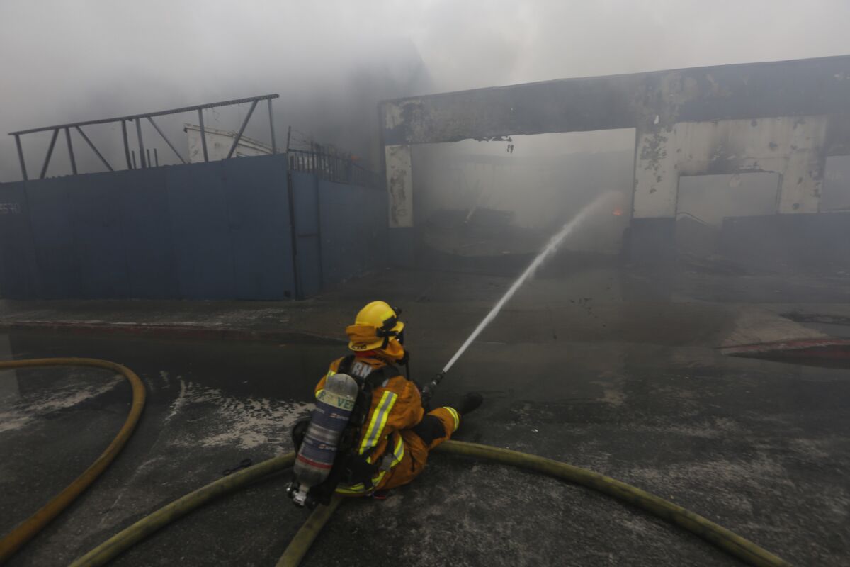 A firefighter battles the stubborn June 14 fire in Maywood at a Fruitland Avenue industrial property.