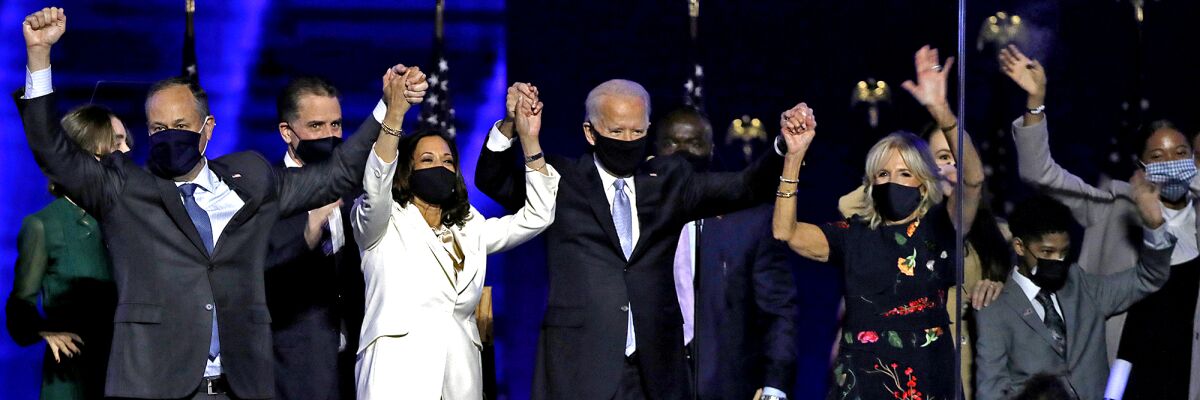 President-elect Joe Biden and Vice President-elect Kamala Harris clasp hands onstage with Jill Biden and Doug Emhoff.
