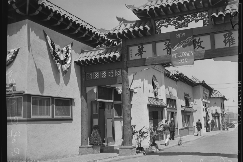 Sign reads "New Chinatown welcomes you" on pagoda-style gate in black and white