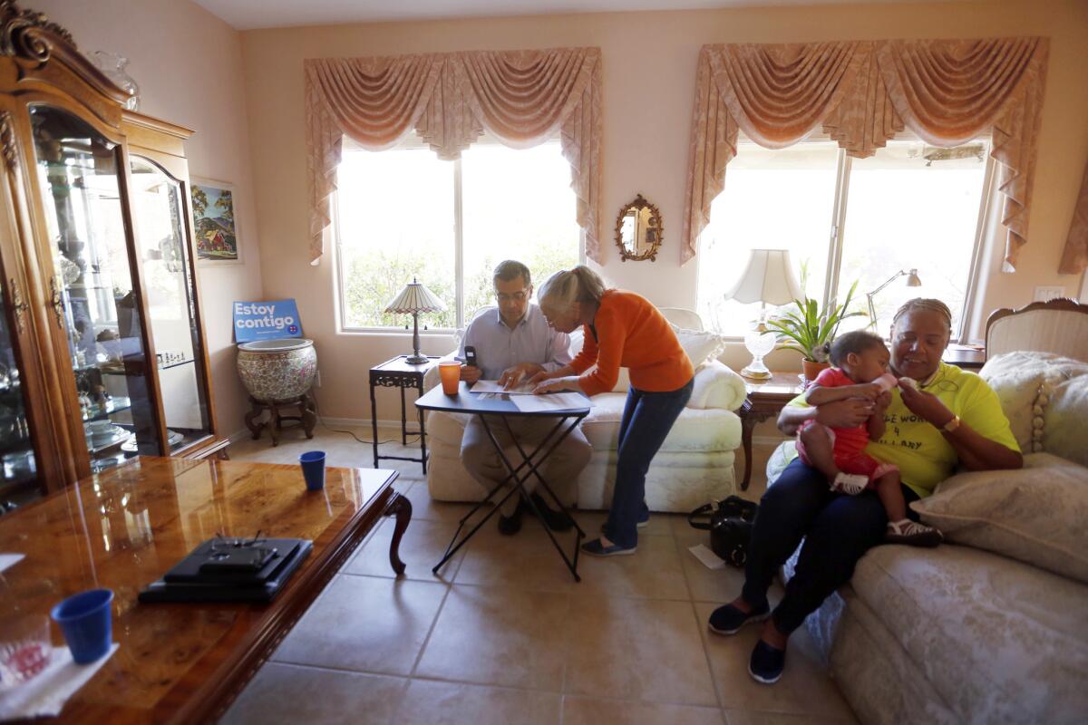 Xavier Becerra, a U.S. representative from Los Angeles, makes a call at the Las Vegas home of Maria Gray, second from left, in support of Hillary Clinton.