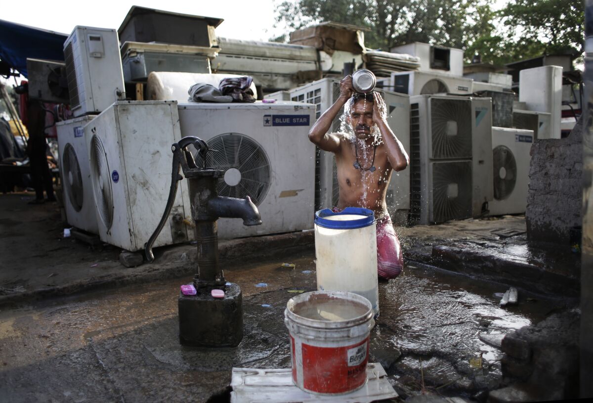 FILE - A migrant daily wage worker bathes at a public well pump on a hot morning in New Delhi, India, Tuesday, May 17, 2016. Scorching summer temperatures, hovering well over 40 degrees Celcius, (104 Fahrenheit) are making life extremely tough for millions of poor across north India. Without access to air conditioning and sometimes even an electric fan, they struggle to cope with the heat in their inadequate homes. (AP Photo/Altaf Qadri, File)