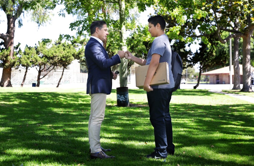 Superintendent Alberto Carvalho, left, gives a fist bump to a teenager at a park